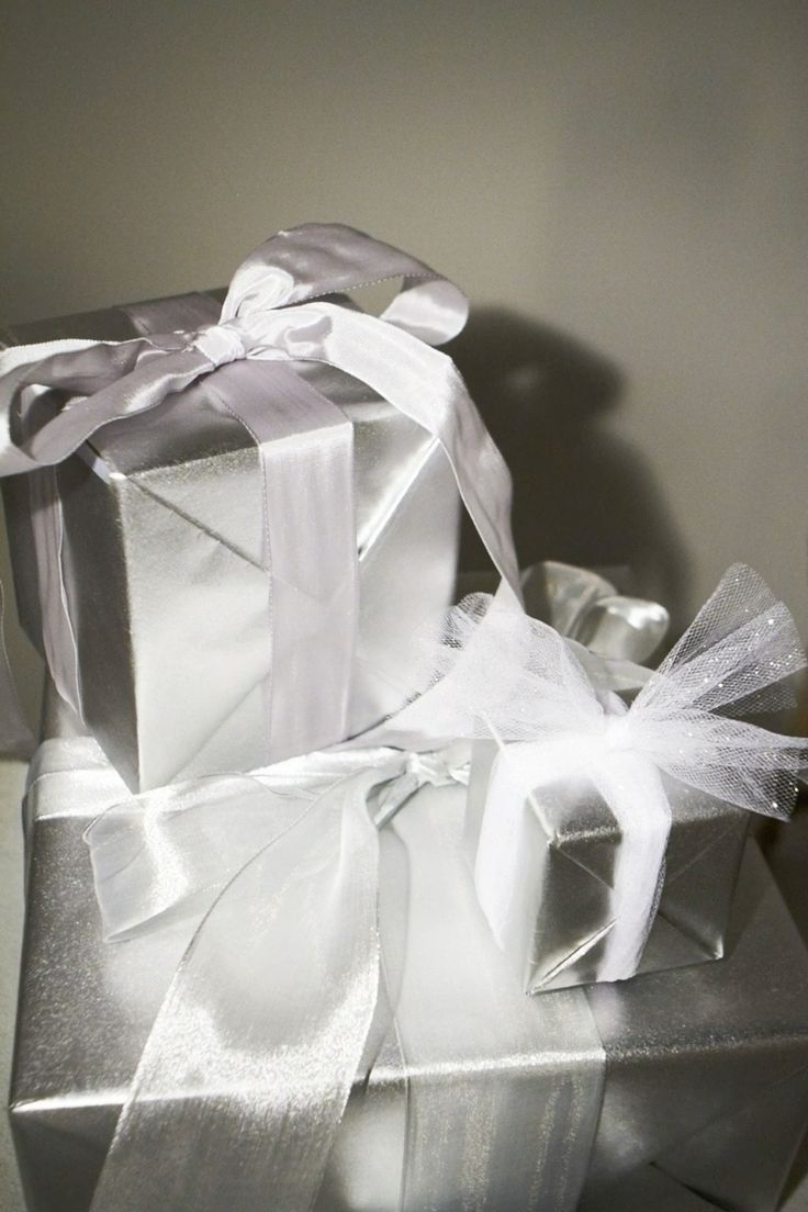 Silver gift boxes wrapped with sheer white ribbon bows.
