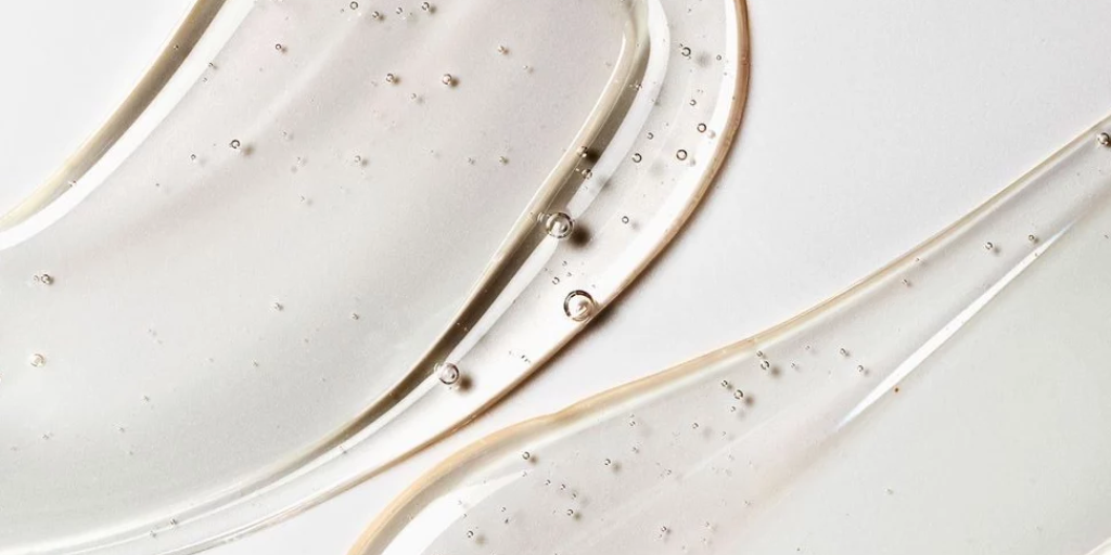 Close-up of clear gel texture with visible air bubbles, swirled on a white surface.