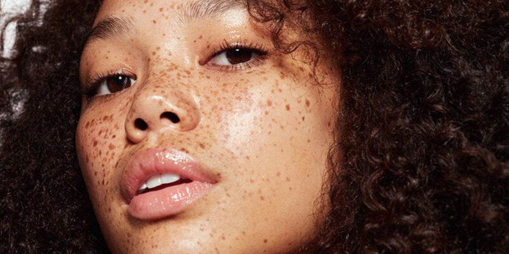 Close-up portrait of a woman with freckles and curly hair.